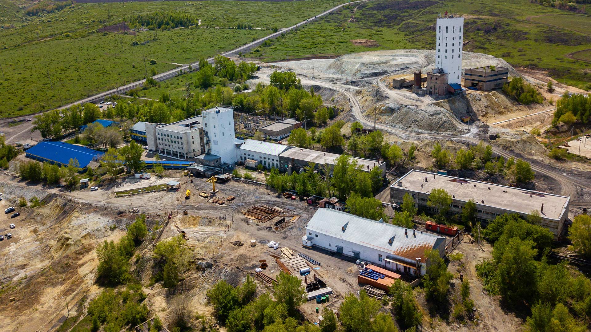 Elevated view of mining work taking place, surrounded by grass, roads, and buildings. 