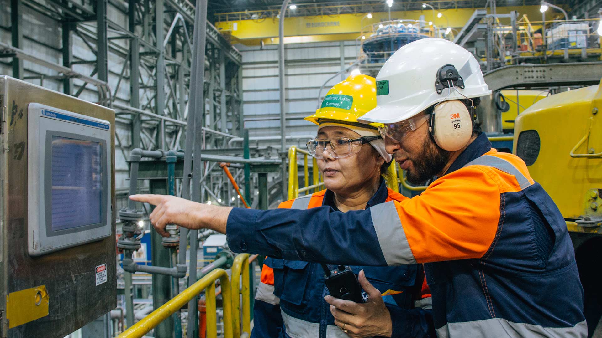 Two workers inside processing facility using a touch screen device. 