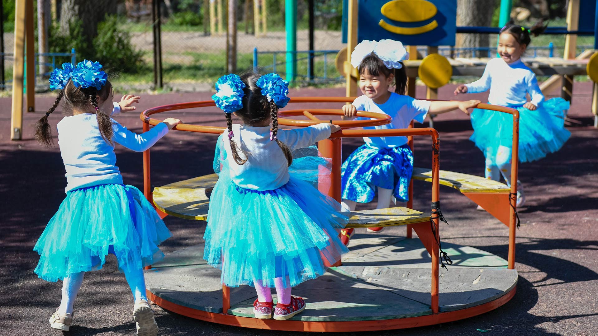 Children in matching turquoise gowns playing in a park. 