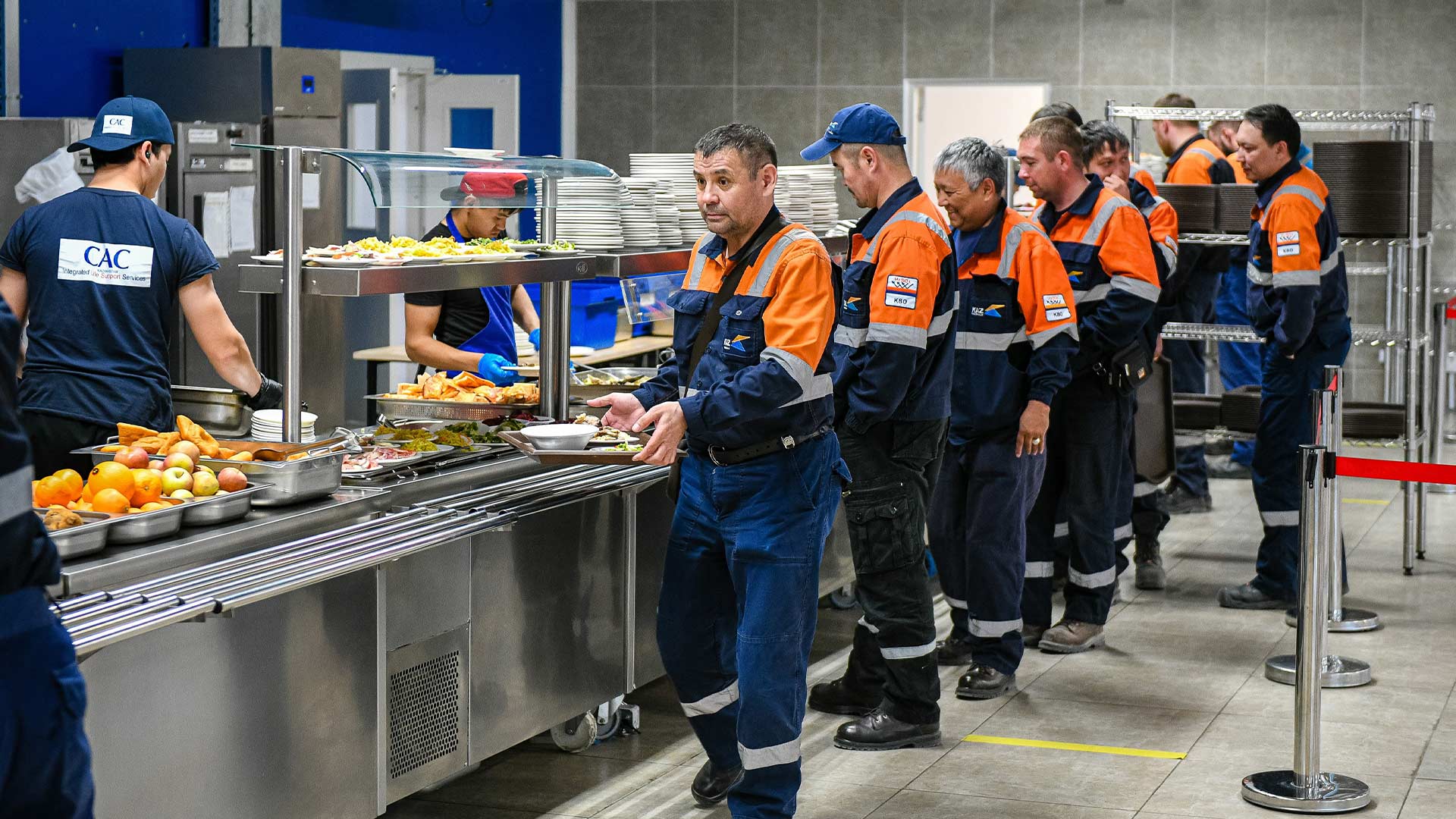 Workings in reflective jackets queuing up for food in the canteen area. 