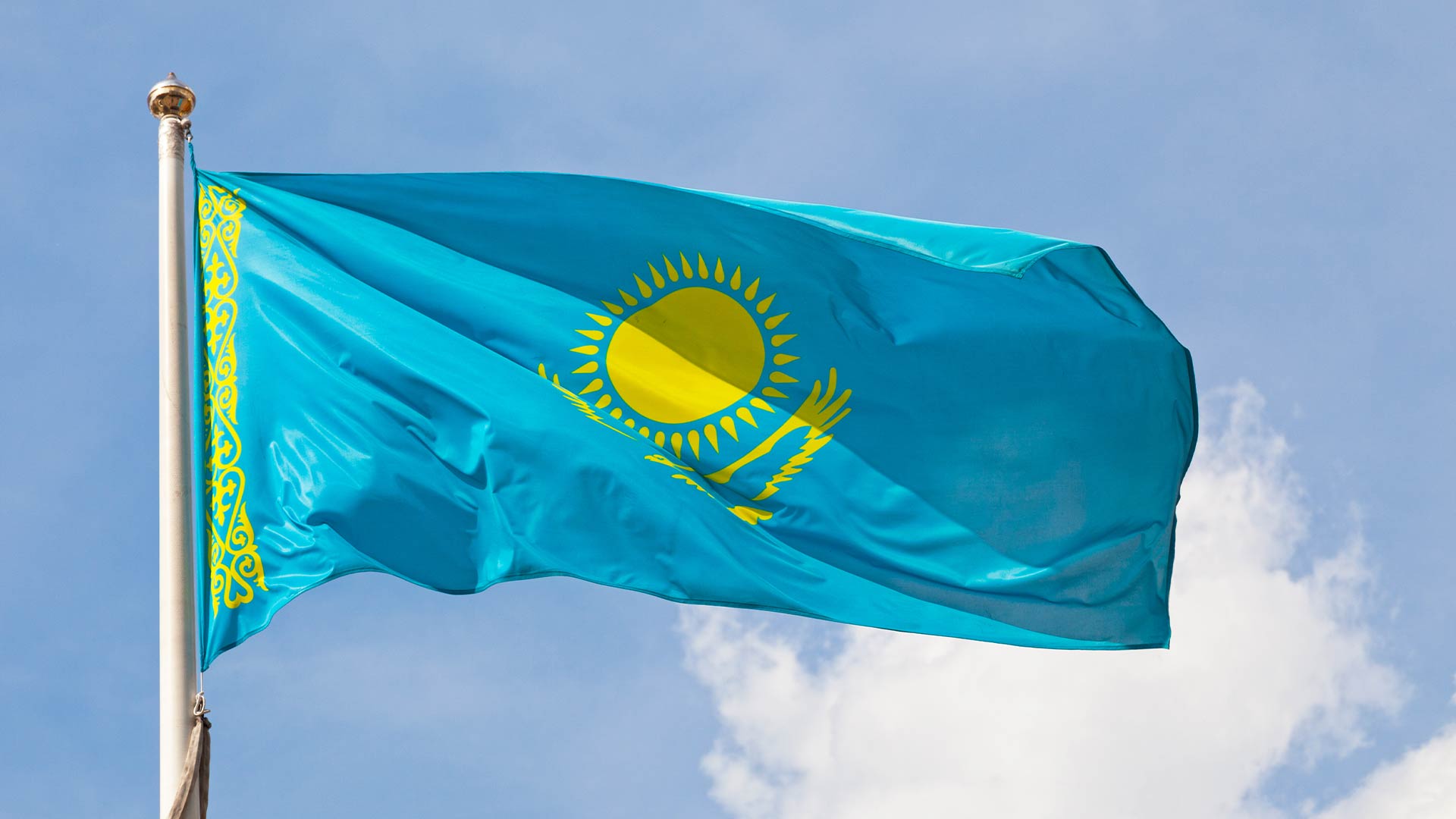 The Kazakhstan flag, a sky-blue rectangle with a yellow sun and steppe eagle soaring beneath it at the centre.